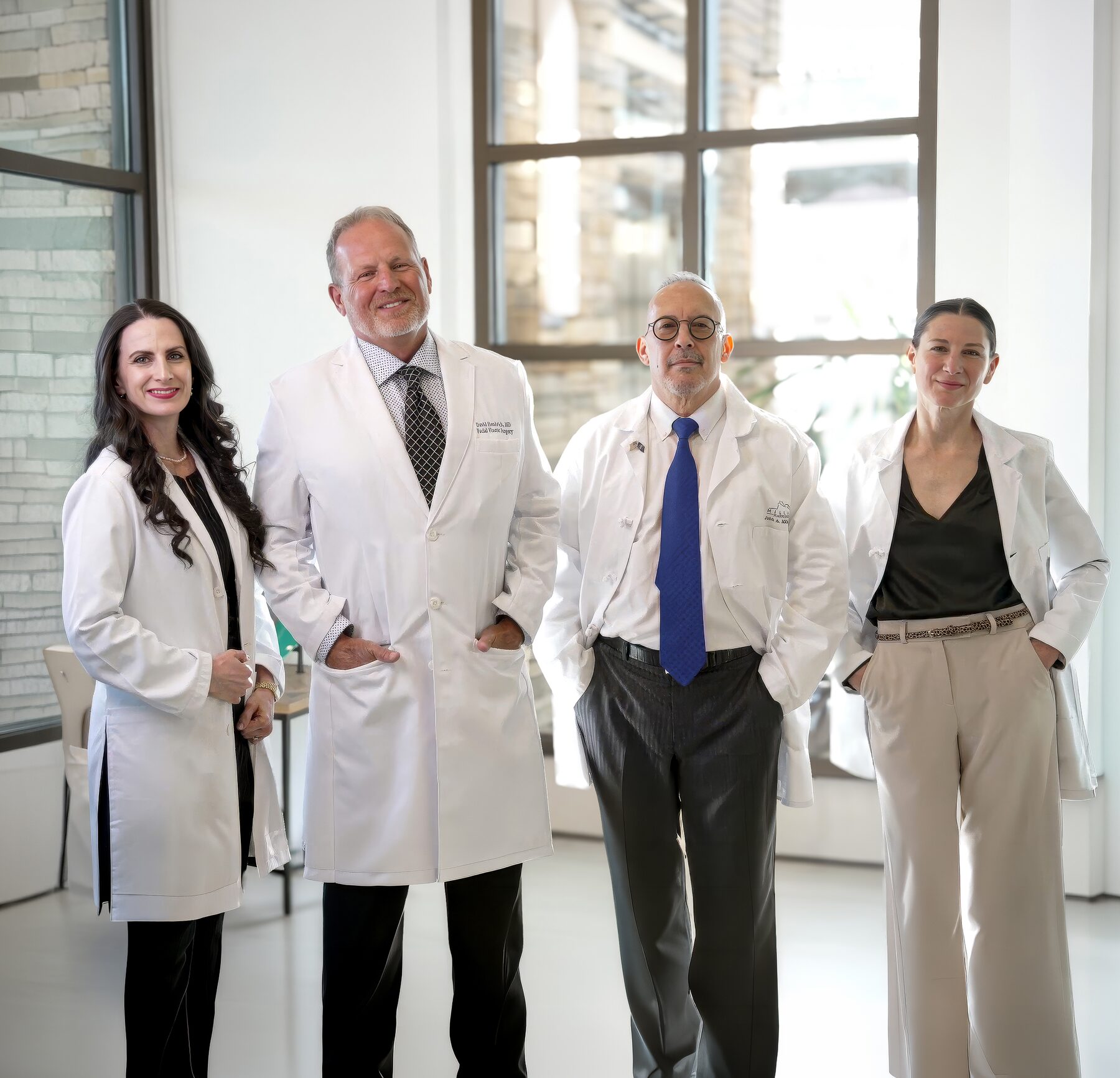 The four Millard Plastic Surgery providers standing together in the practice's sunlit atrium