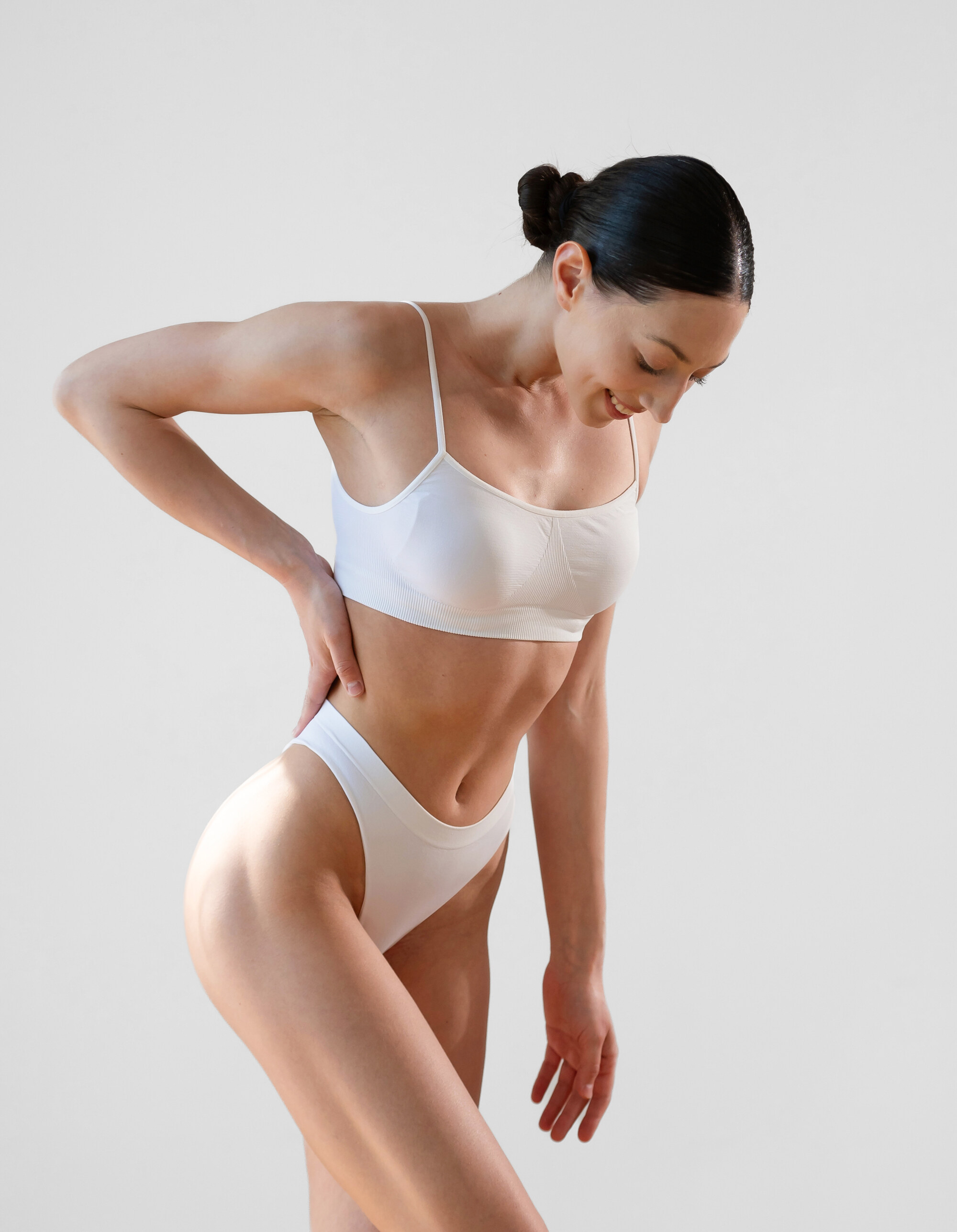 Woman in light activewear showing a flat, contoured abdomen