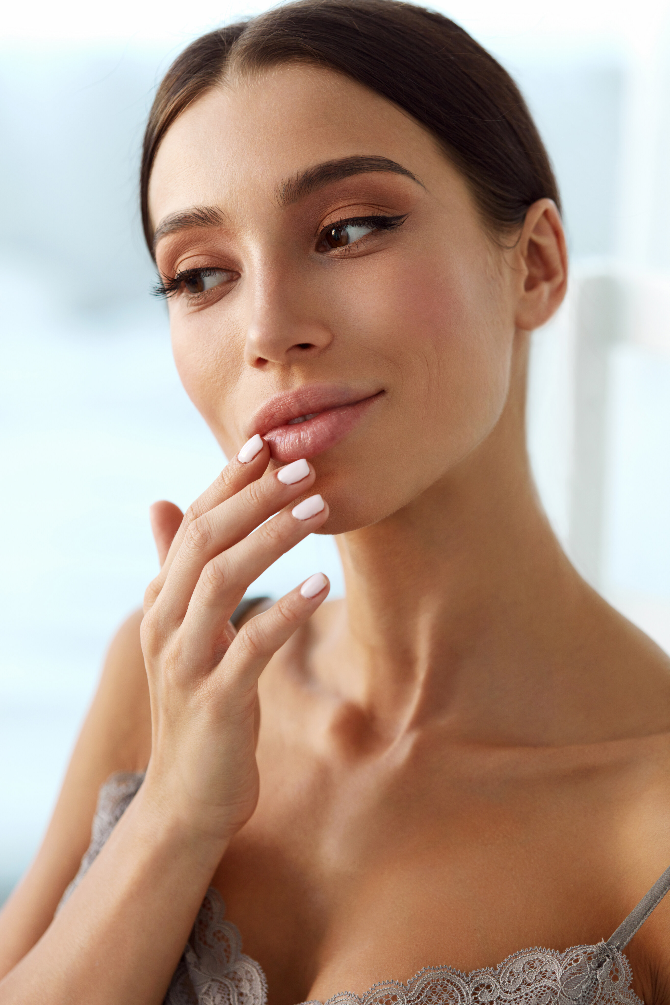Smiling woman with balanced, natural-looking features standing in a bright room